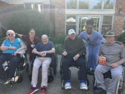4 seniors in wheelchairs with 2 caregivers