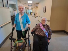 2 senior women in a hallway wearing Welcome sashes